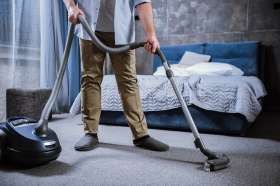 A man vacuuming a carpet